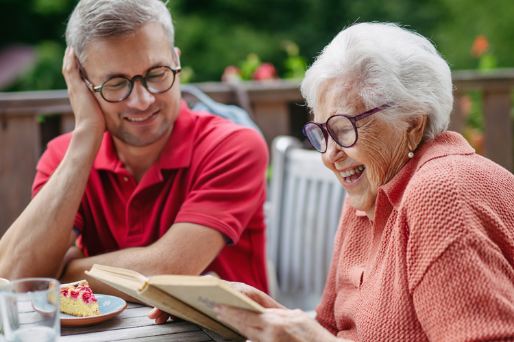 caregiver sitting with senior woman reading