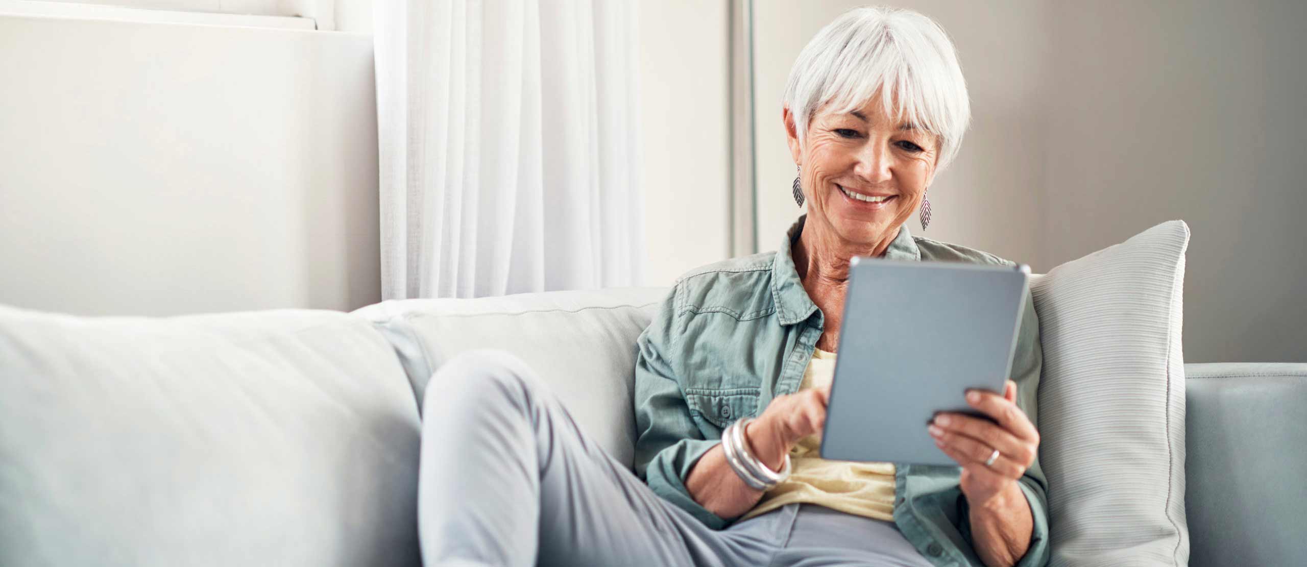 Senior woman using tablet while sitting on couch