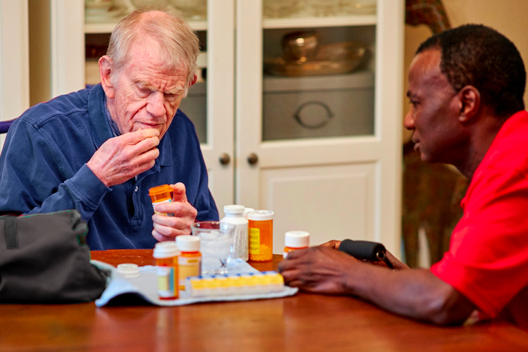 rhythms home care senior man and caregiver with medications blue shirt