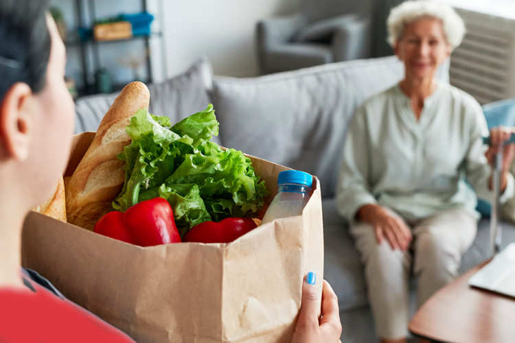 rhythms home care caregiver bringing groceries to client