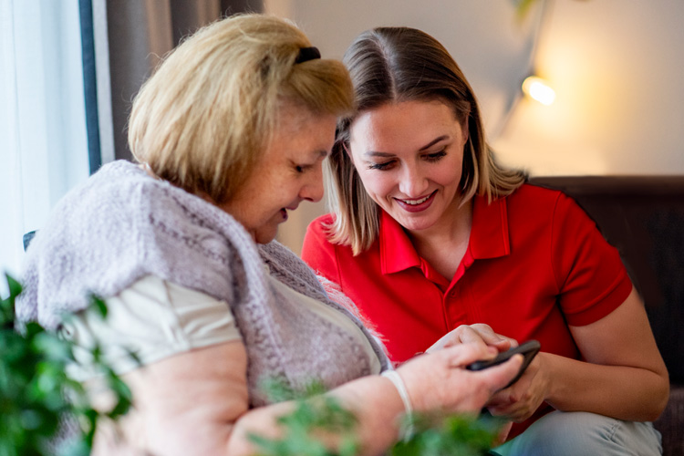 rhythms home care female caregiver with senior woman looking at phone